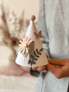 a woman holding a paper cone with flowers on it and a butterfly decoration on the top