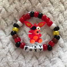 a red and black beaded bracelet with an orange fox on it's face