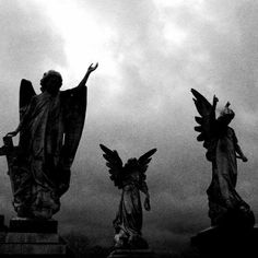 black and white photograph of angel statues against cloudy sky