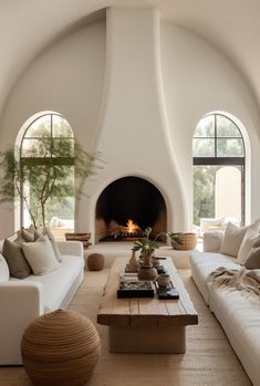 a living room with white couches and a fire place in the middle of it