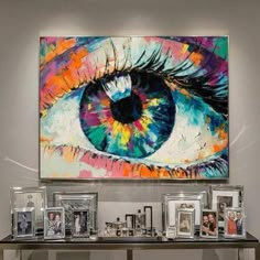 an eye is shown on the wall above a table with pictures and framed photos in front of it