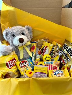 a teddy bear sitting in a yellow box filled with candy and candies for someone's birthday