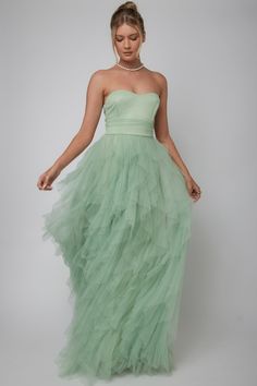 a woman wearing a green dress with a strapless top and tiered tulle skirt