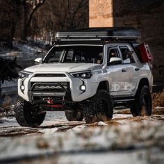 a white truck driving down a street next to a tall brick building in the snow