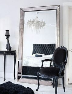 a black chair sitting in front of a large mirror