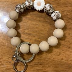 a bracelet with white and black beads on a wooden table next to a keychain