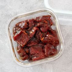 a glass container filled with meat sitting on top of a table