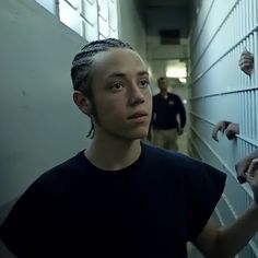 a woman standing in a jail cell with her hands on the wall and two men behind her