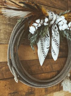 a wreath with feathers and cotton on top of a wooden wall next to a rope