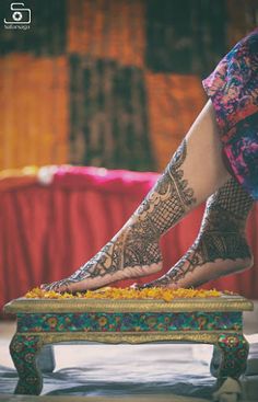 a woman's feet with hennap on top of a small table in front of a red curtain