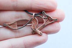 a hand holding a piece of jewelry in it's left hand, with the end of an animal shaped brooch