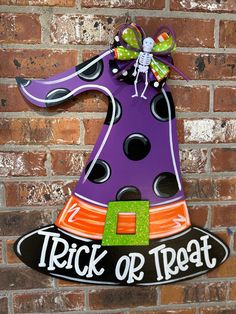 a purple and black sign that says trick or treat on the side of a brick wall