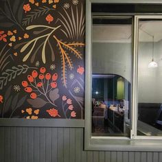 the wall is decorated with colorful flowers and leaves, along with an open window to let in natural light