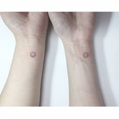 two wrist tattoos with circles on them, one has a small dot in the middle