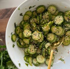 a white bowl filled with sliced cucumbers and herbs