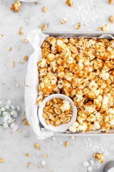 a tray filled with popcorn sitting on top of a table next to some white flowers