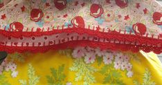 the top portion of a dress with red lace trims and flowers on yellow fabric