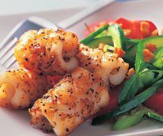 a white plate topped with shrimp and veggies next to a knife and fork