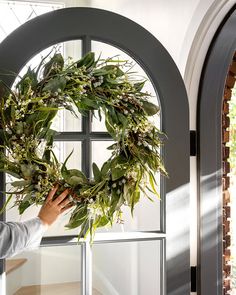 a man is holding a wreath on the front door