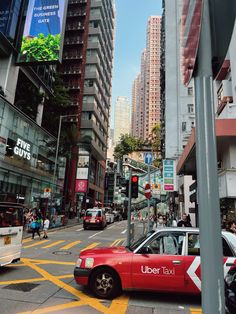 a red taxi cab driving down a street next to tall buildings