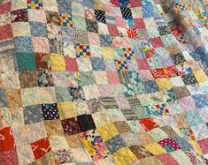 an old quilt is laying on top of a tablecloth that has been made into a blanket