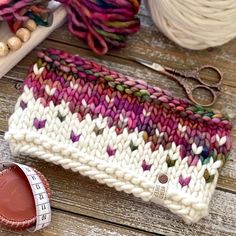 a close up of a knitted bag next to a pair of scissors and yarn