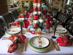 the table is set for christmas dinner with red and green decorations