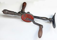 an old pair of scissors with red and black handles on white background, cut out from metal