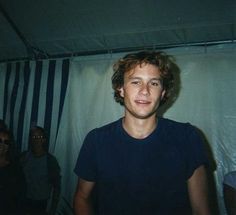 a young man standing in front of a white curtain