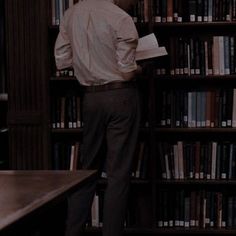 a man standing in front of a bookshelf with lots of books on it