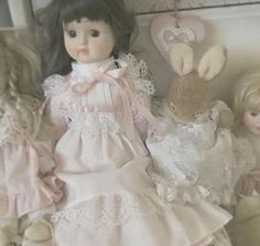 two dolls sitting next to each other on a bed with white sheets and laces