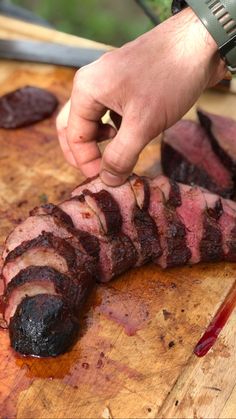 a person is slicing up some meat on a cutting board