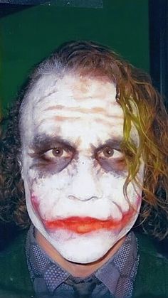 a man dressed up as the joker with his hair in curls and makeup is looking at the camera