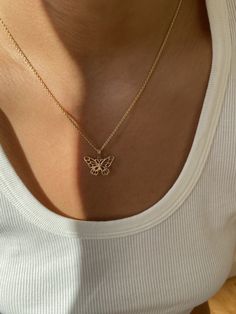 a woman wearing a gold necklace with a butterfly charm on it's back neck