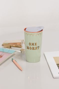 a cup with the words one more on it next to other items and notebooks