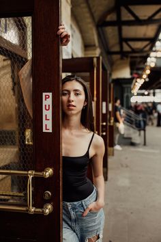 a woman standing in front of a door with her hand on the side of it