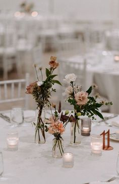 there are many vases with flowers on top of the table at this wedding reception