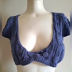 a female mannequin wearing a blue knitted crop top with an open back