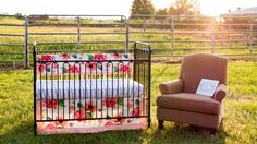 a baby crib and chair in the grass near a fence with a sign on it