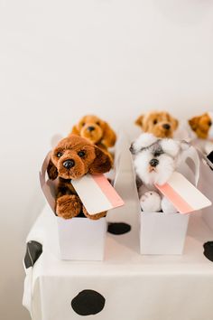 small stuffed dogs sitting in white boxes on top of a polka dot tablecloth covered table