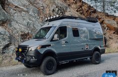 the van is parked on the side of the road next to some rocks and trees