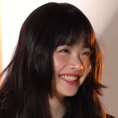 a woman with long black hair smiles at the camera