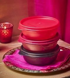 a stack of plastic containers sitting on top of a table next to a red candle