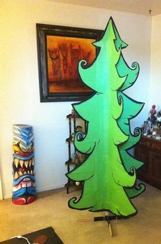 a cardboard christmas tree sitting on top of a carpeted floor next to a painting