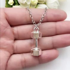 a hand holding a silver necklace with two cubes attached to it