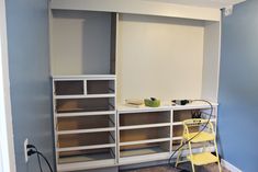 an empty room with shelves, chairs and a yellow chair in the corner next to it