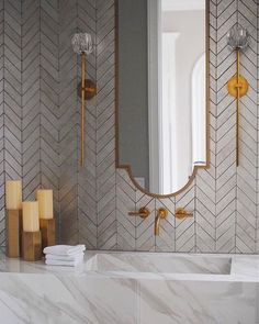 a bathroom with marble counter tops and gold accents on the mirror, along with candles