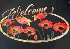 a welcome sign with red and yellow flowers on black table cloth at an outdoor event