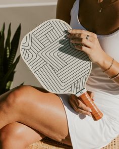 a woman sitting on a chair holding a white and black plate with geometric designs in it