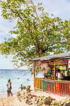 a colorful bar on the beach with people swimming in the water